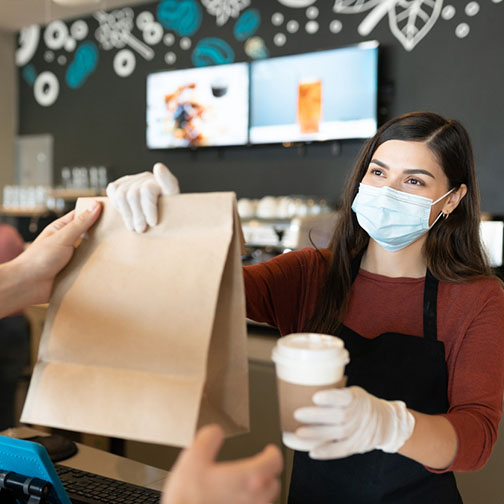 Female Barista Giving Parcel And Coffee To Customer